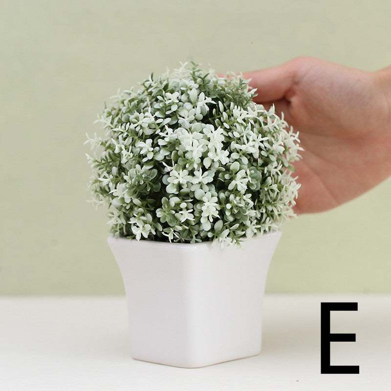 White artificial mini plant in white square pot, held by hand for scale – Pausadesk