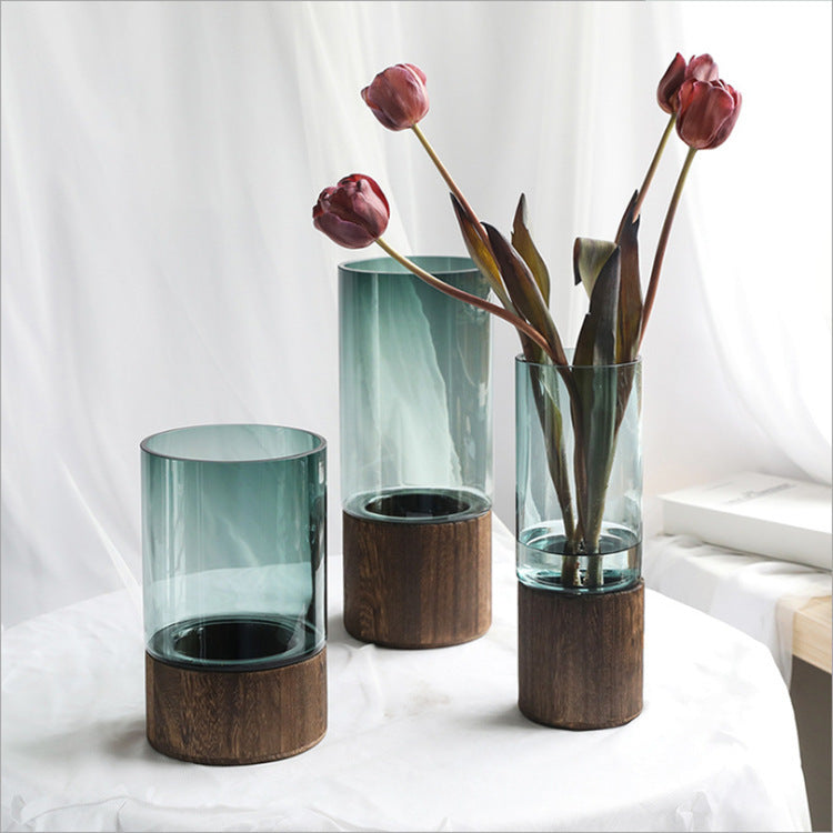 Straight-line clear glass vase with dried stems on a wooden table