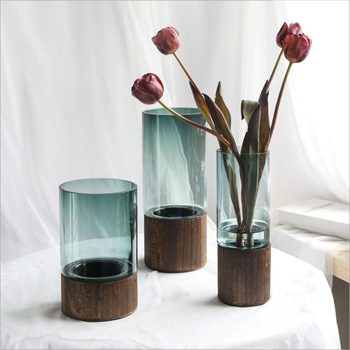 Straight-line clear glass vase with dried stems on a wooden table