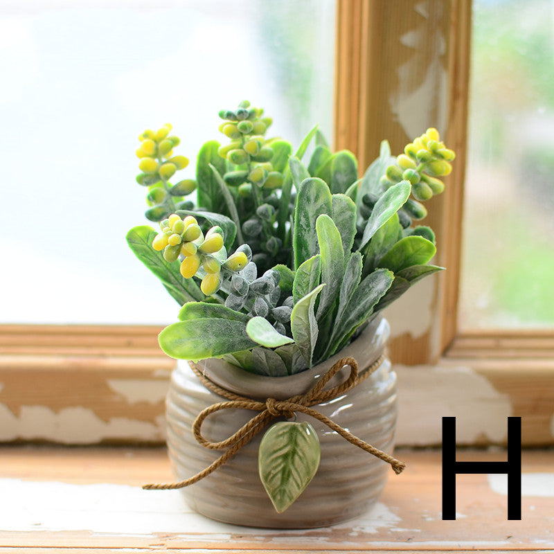 Green foliage with yellow buds in gray ceramic jar tied with twine on windowsill – Pausadesk