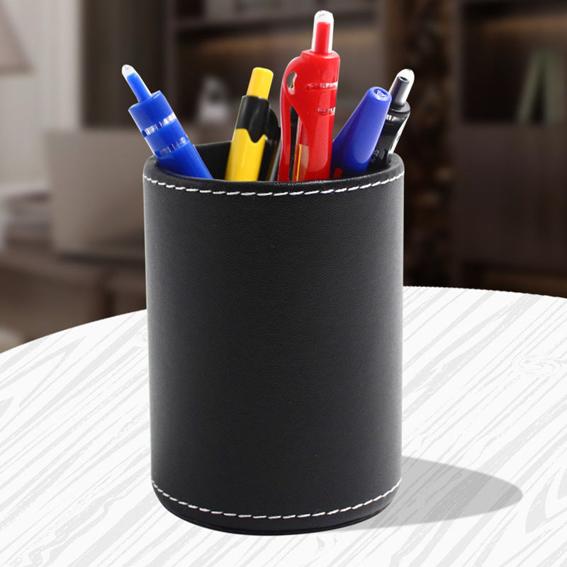 Round black leather pen holder with pens on a desk