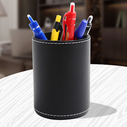 Round black leather pen holder with pens on a desk