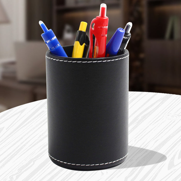 Round black leather pen holder with pens on a desk